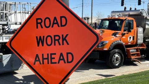 Road Work Ahead sign and tandem truck within a work zone.