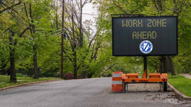Message board displaying work zone ahead with Macomb County logo.