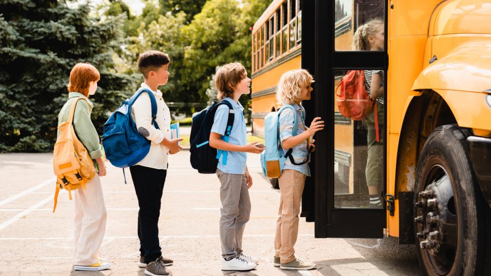 children line up next to a school bus